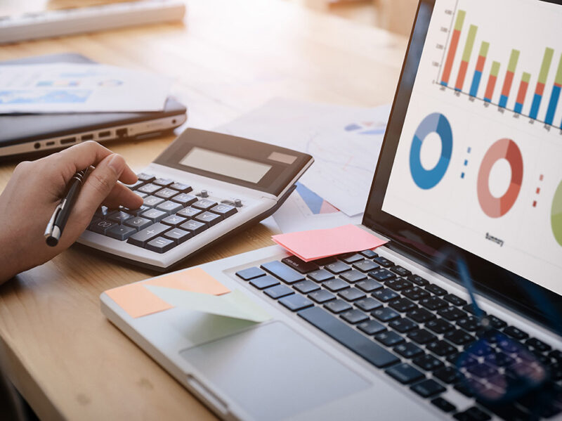 business woman uses a calculator to calculate the company's performance figures, graphs the monthly graphs for the meeting.