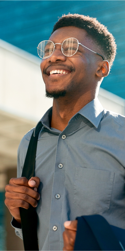 A man in glasses and a button down shirt smiling warmly.