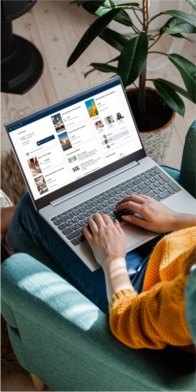 A woman sitting on a couch, engrossed in her laptop, focused on the PerformX platform.