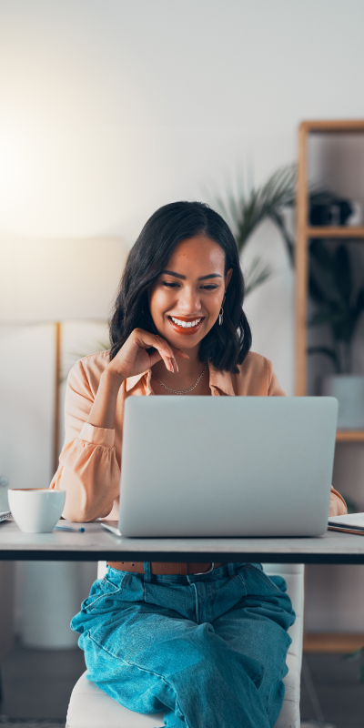 a Woman Smiling at a Desk with a Laptop, Radiating Positivity and Productivity.