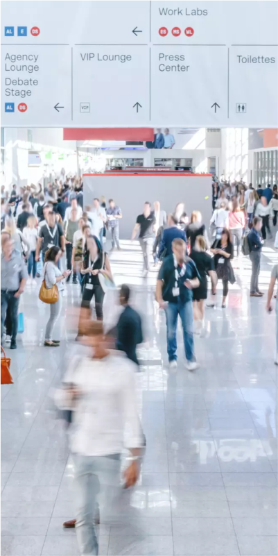 A bustling conference with a diverse crowd of travelers walking.