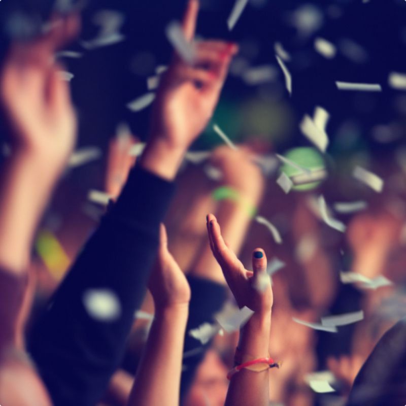 Confetti raining down from jubilant concertgoers' hands, adding a vibrant touch to the lively atmosphere.