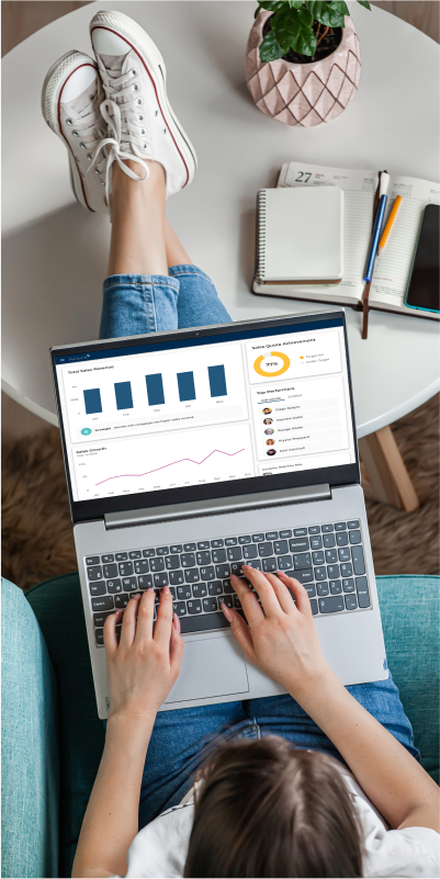 A woman sitting on a couch, engrossed in her laptop, focused on the PerformX platform.