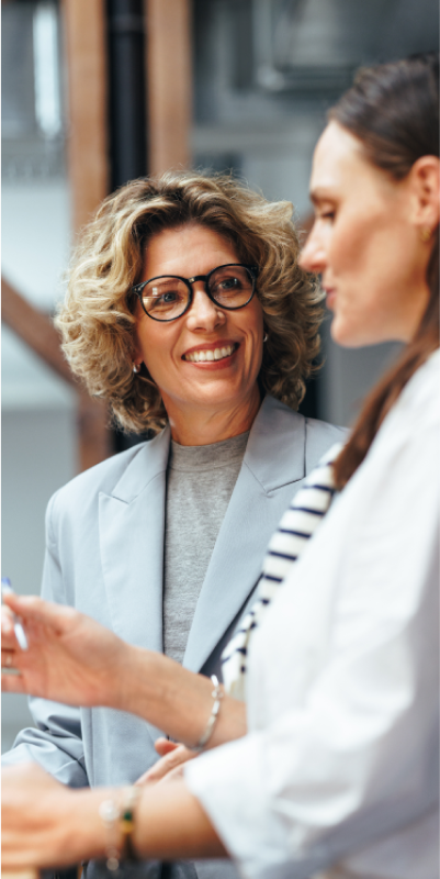 Two women engaged in a conversation in a professional office environment.