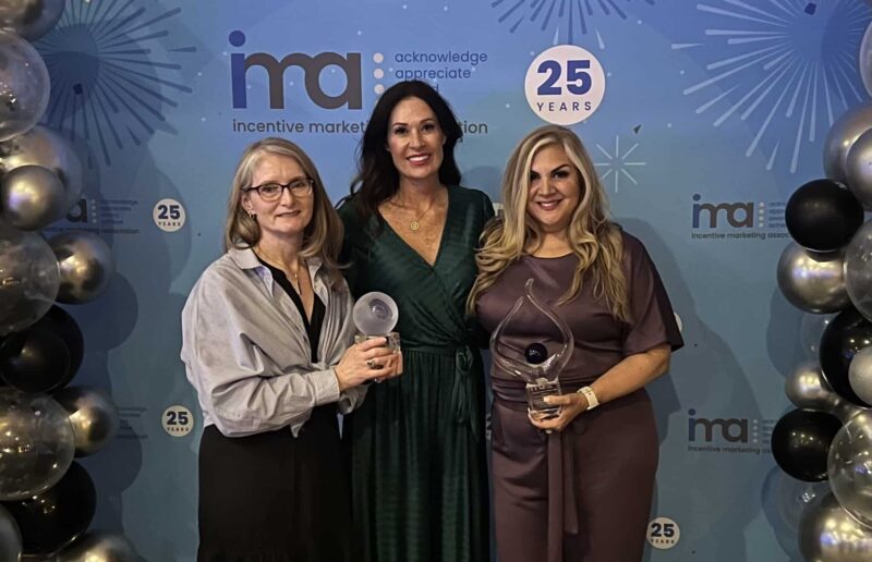 Cheryl Taylor, Richelle Suver and Pam Pelino stand side by side holding up their two IMA awards.