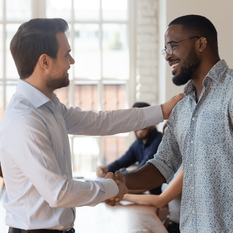 A manager at an insurance company shaking hands with a new recruit.
