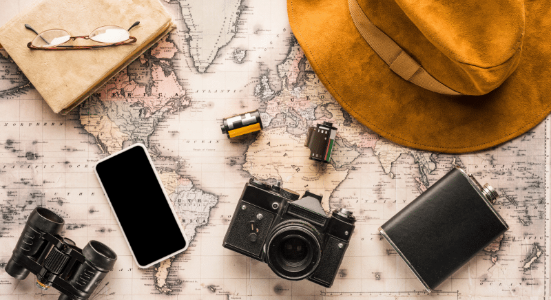 A hat and camera equipment are on top of a flat map.